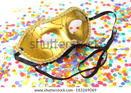 Golden carnival mask with ribbons on a confetti background