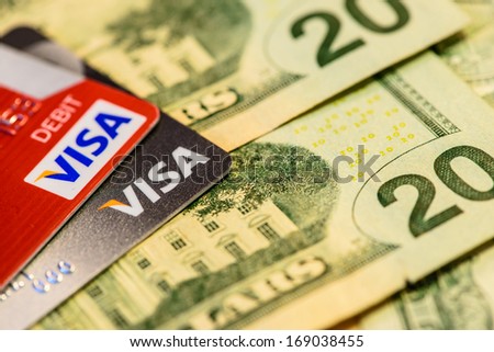 BOSTON, USA - DECEMBER 29, 2013: Visa Credit and Debit Cards Over Dollar bills
