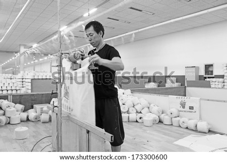 LUANNAN COUNTY - DECEMBER 20: worker packing cotton reel thread in a production workshop, in the ZeAo spinning LTD., on December 20, 2013, Luannan county, hebei province, China.
