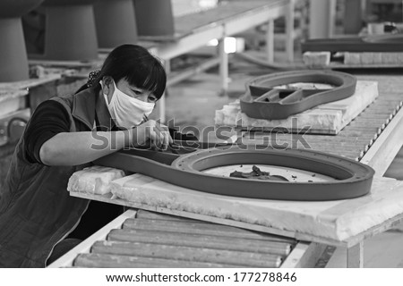 LUANNAN COUNTY - JANUARY 5: Woman worker repairs ceramic semi-finished products in a warehouse, in the ZhongTong Ceramics Co., Ltd. January 5, 2014, Luannan county, Hebei Province, China.