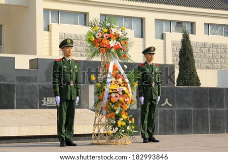 LUANNAN COUNTY - MARCH 22: Armed police soldiers carrying flower basket, in Pan Dai village massacre memorial building exterior, on March 22, 2014, luannan county, hebei province, China