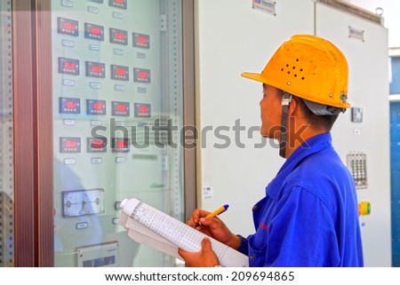 TANGSHAN - JUNE 18: Technical personnel in the control room meter reading record, in a iron and steel co., on June 18, 2014, Tangshan city, Hebei Province, China