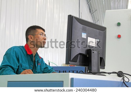 LUANNAN COUNTY - AUGUST 23: technicians staring at computer monitors in a production line, on august 23, 2014, Luannan County, Hebei Province, China
