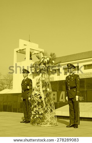 LUANNAN COUNTY - MARCH 22: Armed police soldiers carrying flower basket, in Pan Dai village massacre memorial building exterior, on March 22, 2014, luannan county, hebei province, China