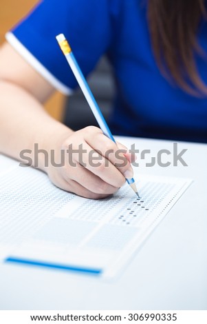 Student filling out answers to blue answer sheet with blue pencil