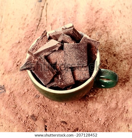 A cup of chocolate chips on a wooden table.