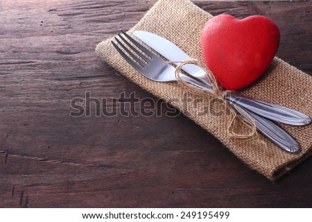 Valentines day dinner. Seasonal old dark table with cutlery and heart.