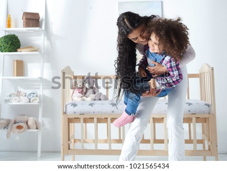 happy young mother playing with her daughter lift her up at home premium light modern interior with crib on background weekend concept