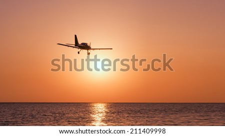 Small plane over the sea on a sunset