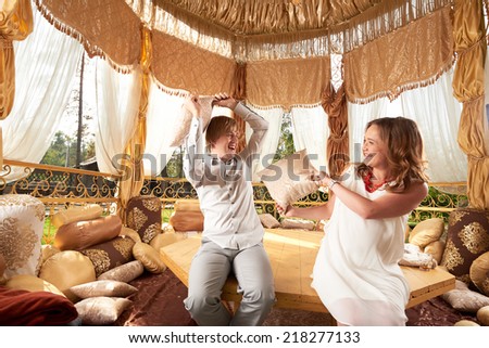 Young couple with pregnant woman fights with pillows