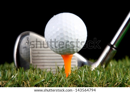 Golf iron ready to hit golf ball on black background