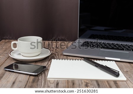 office working desk with laptop, notepad, smartphone and coffee cup