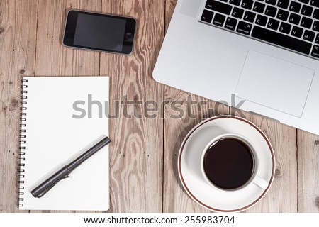 office working desk top view with laptop, smartphone, notepad and coffee cup