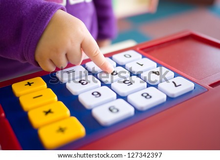 kids finger pressing toy calculator. abstract of fun learning and mathematical thinking.