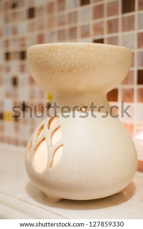 Cream porcelain aroma therapy oil burner decorated in front of the mosaic wall