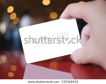 Hand holding white dummy card (to be replaced with your own) in the elegance atmosphere