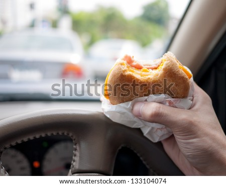 Driver eating burger in the car as the traffic is very bad in the morning. Abstract of urban life.