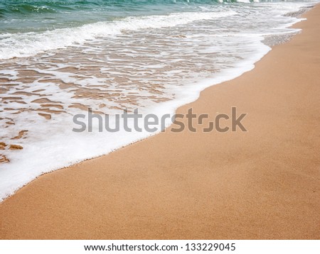Clean and white wave on the beach with the smooth sand. Remembrance of the last summer trip.