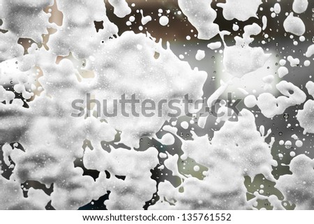 White foam drops on the wet window as it is going to be cleaned