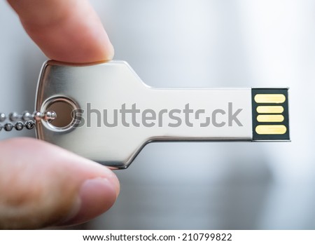 Macro image of a hand holding key-shaped USB drive in concept of technology security