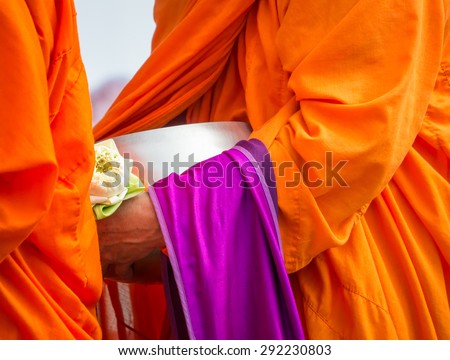 Buddhist monk holding alms bowl and lotus flower in religious concept