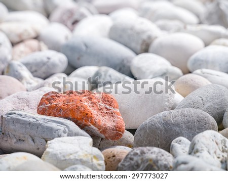 Orange stone among other stones in concept of uniqueness
