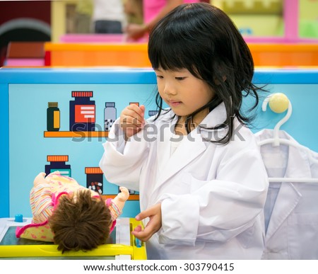 Adorable asian girl role playing doctor occupation wearing white gown uniform
