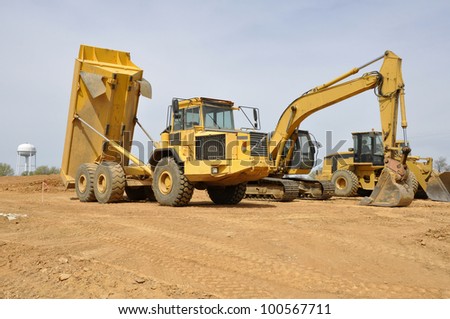 several large construction vehicles, including a dump truck and backhoe