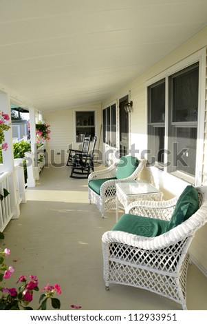 quaint covered porch with white wicker chairs and black rocking chairs