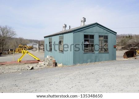 old green shed or utility storage building by a construction area