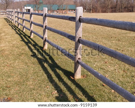post and split rail fence by a field