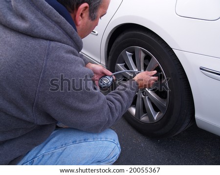 man checking air pressure in car tire