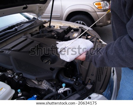man checking oil level in car engine