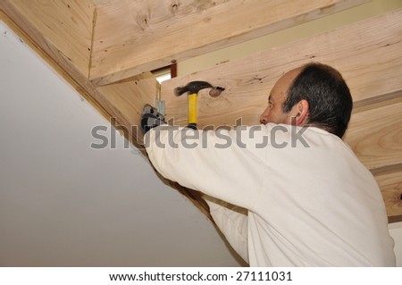 man nailing a board and doing home remodeling