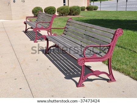 two empty outdoor benches by a concrete walkway
