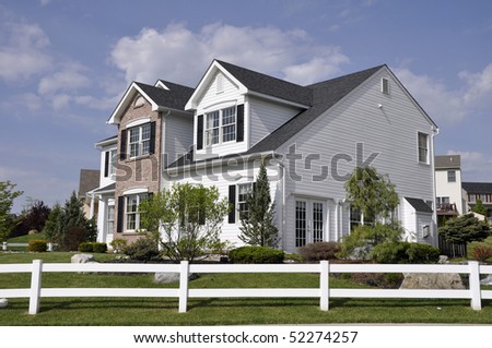 Two story modern home with a white wooden fence around the yard