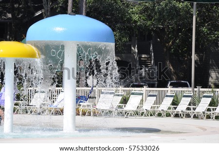 Children\'s play area by an inground pool,  The pool is at a resort and the pool area is surrounded by lounge chairs