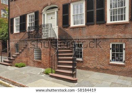 Exterior of an old red brick home with a double staircase.  The home is in Savannah, Georgia.