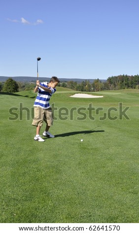 Young boy ready to drive a golf ball on a golf course.