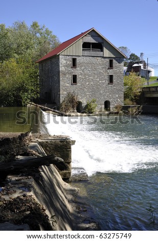 Old stone grist mill by a dam and waterfall.  The grist mill is in Lehigh County, Pennsylvania