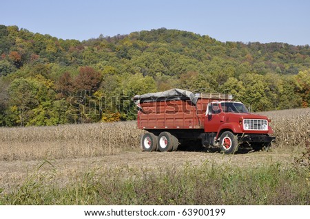 Red farm truck by a field of cut down corn.