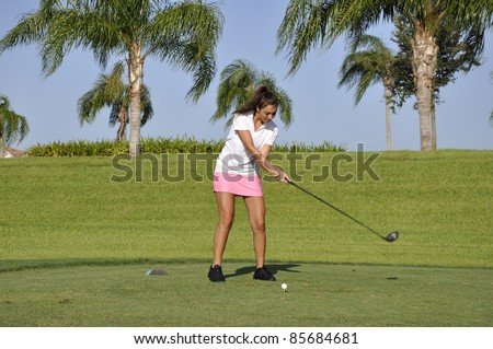 Teenage girl ready to drive a golf ball on a golf course in Naples, Florida