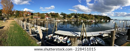 panoramic view of the Rockport Marine harbor in Maine.  There are many boats moored by the dock as well as many boats anchored in the water.