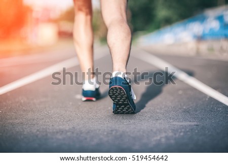 Fitness Runner feet on track focus on sport shoe. Urban Jogger running Getting ready to start