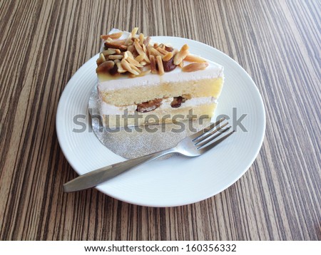 Snack is vanilla cake with a delicious almond paste in a white plate on a wooden background pattern.