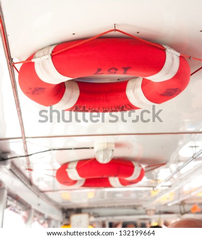 Two orange ring buoys hangs poolside.