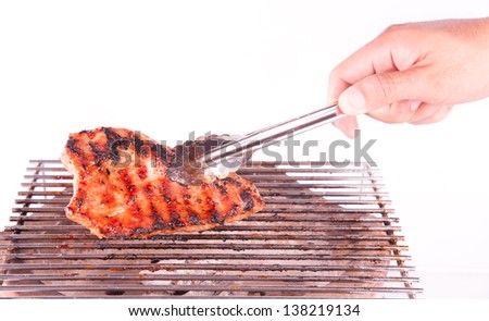 Closeup of someone turning a tasty steak cooking on a fire