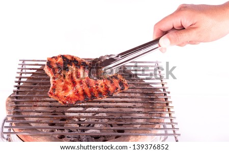 Closeup of someone turning a tasty steak cooking on a fire