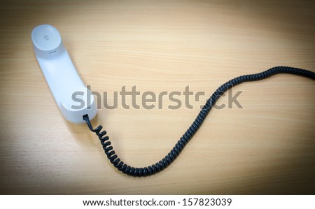Elevated View of a white Telephone Receiver on a wooden table,