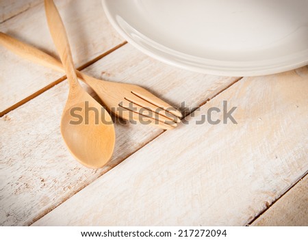 plate with fork and spoon on white wood